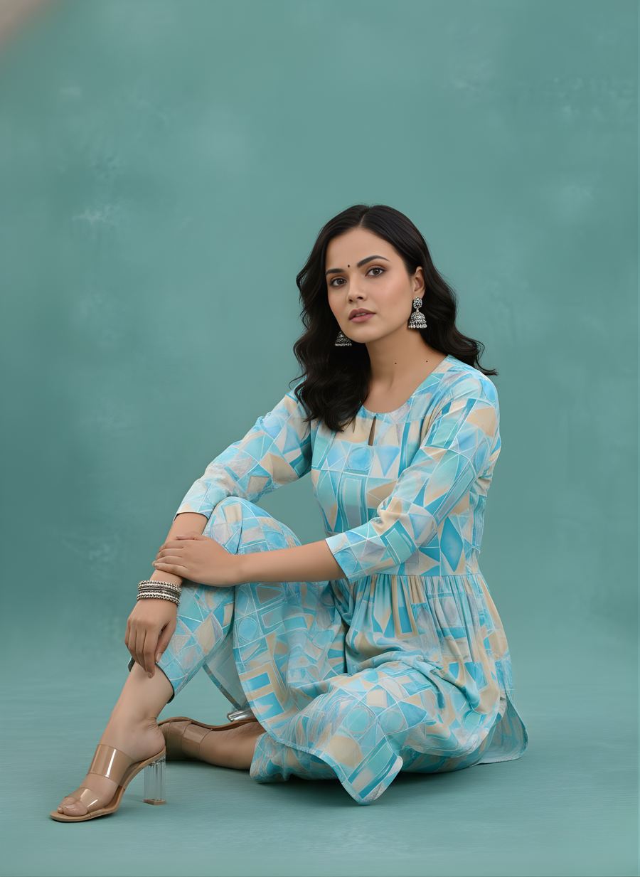 Woman wearing a light blue patterned dress sitting on a teal background