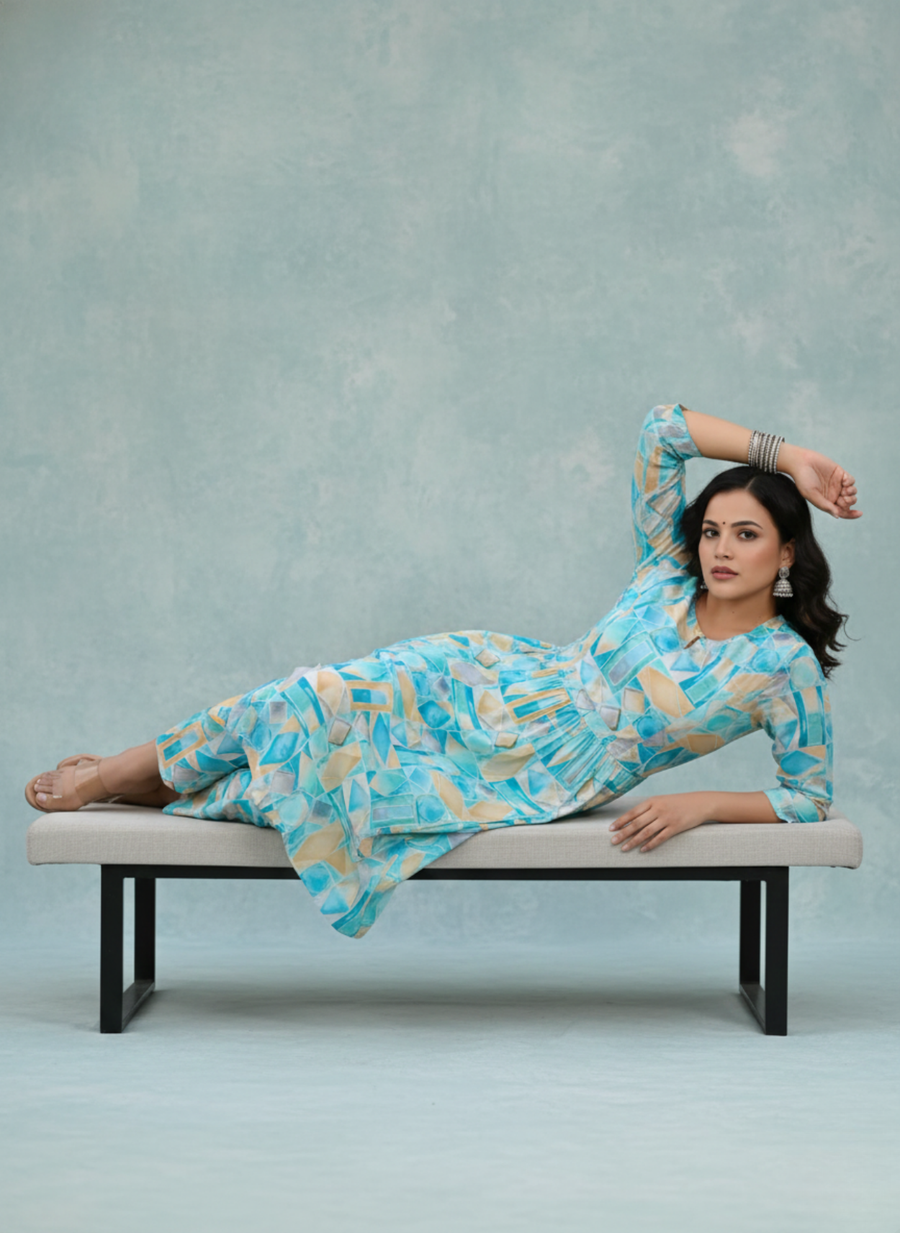 Woman in a blue and white patterned dress lying on a bench against a gray background
