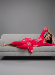 Woman in a pink traditional outfit lying on a gray couch against a gray background