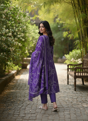 Woman in a purple outfit standing in a garden with greenery